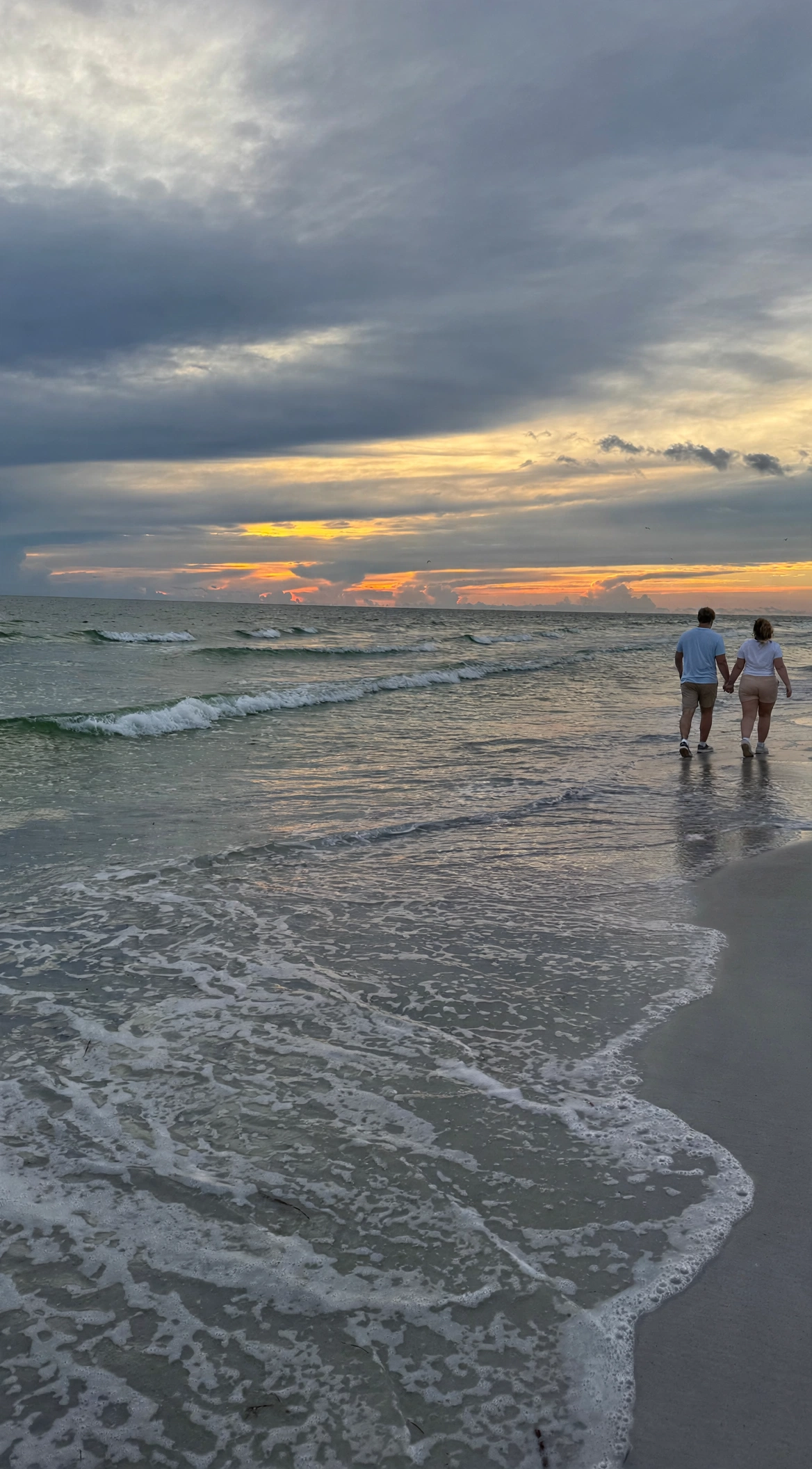Couple holding hands walking on Upham Beach at sunset, St. Pete Beach Florida